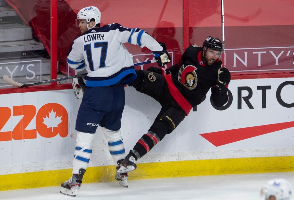 CP
Winnipeg Jets centre Adam Lowry, left, checks Ottawa Senators centre Michael Amadio along the boards during the first period. THE CANADIAN PRESS/Adrian Wyld