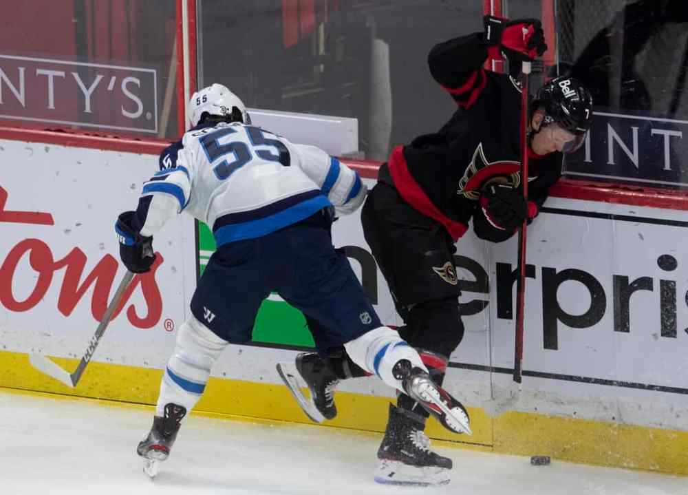Ottawa Senators left wing Brady Tkachuk gets the puck under control after colliding with Winnipeg Jets centre Mark Scheifele along the boards during the first period. THE CANADIAN PRESS/Adrian Wyld