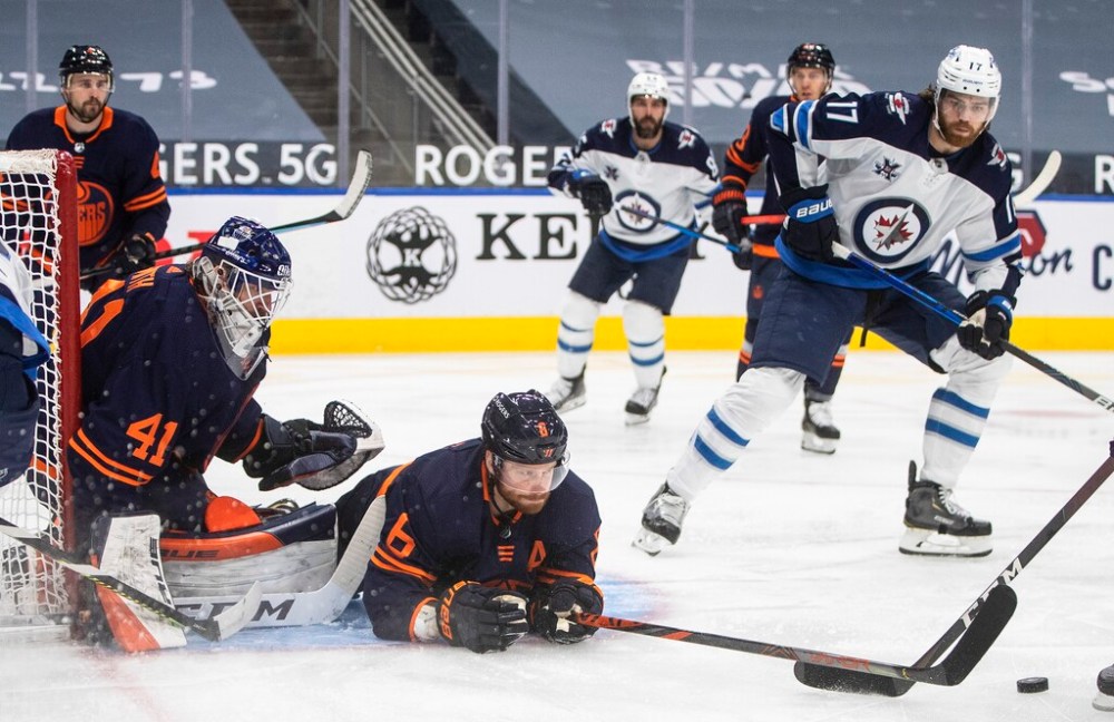 Edmonton Oilers goalie Mike Smith looks for the puck as Adam Larsson blocks the shot and Winnipeg Jets' Adam Lowry looks for the rebound during the first period in Edmonton on Wednesday. THE CANADIAN PRESS/Jason Franson