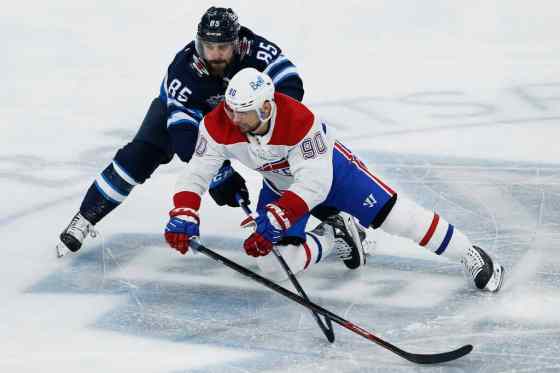 Winnipeg Jets' Mathieu Perreault (85) and Montreal Canadiens' Tomas Tatar (90) go for the puck during first period NHL action in Winnipeg on Thursday, February 25, 2021. THE CANADIAN PRESS/John Woods