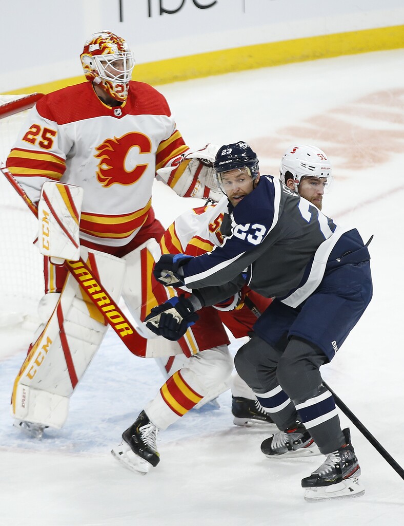 Winnipeg Jets' Trevor Lewis and Calgary Flames' Noah Hanifin battle for position in front of Flames goaltender Jacob Markstrom during the first period Thursday. THE CANADIAN PRESS/John Woods