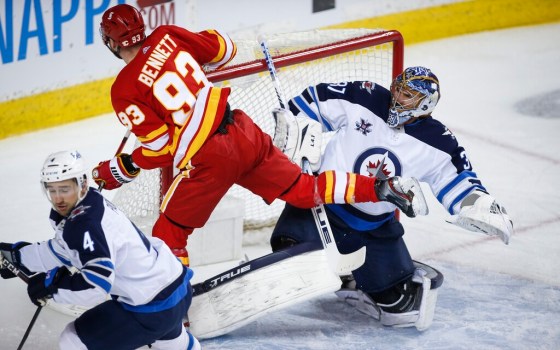 Winnipeg Jets goalie Connor Hellebuyck, right, reacts as Calgary Flames' Sam Bennett crashes into him during first period NHL hockey action in Calgary, Tuesday.THE CANADIAN PRESS/Jeff McIntosh