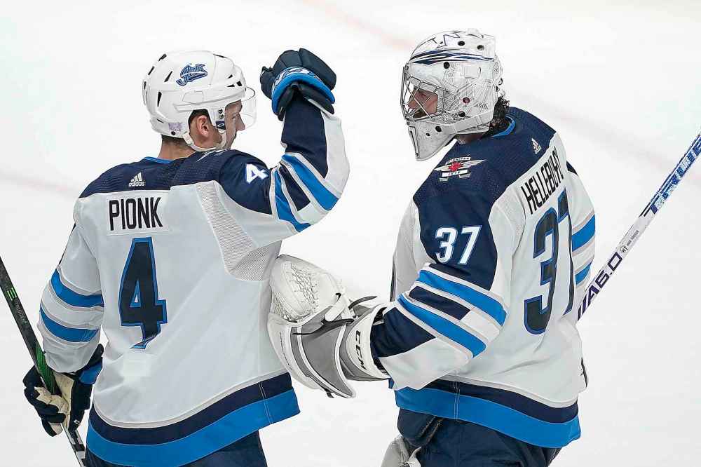 (AP Photo/Tony Avelar)
Jets goaltender Connor Hellebuyck celebrates Friday’s win over the Anaheim Ducks with defenceman Neal Pionk.