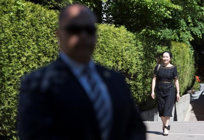 A security guard looks on as Meng Wanzhou, chief financial officer of Huawei, leaves her home to go to B.C. Supreme Court in Vancouver, Wednesday, May 27, 2020. THE CANADIAN PRESS/Jonathan Hayward