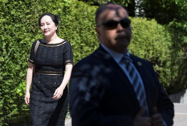 A security guard looks on as Meng Wanzhou, chief financial officer of Huawei, leaves her home to go to B.C. Supreme Court in Vancouver, Wednesday, May 27, 2020. THE CANADIAN PRESS/Jonathan Hayward
