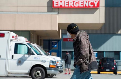 A man wears a protective face mask as he walks past the emergency department of the Royal Columbian Hospital in New Westminster, B.C. Friday, April 3, 2020. THE CANADIAN PRESS/Jonathan Hayward