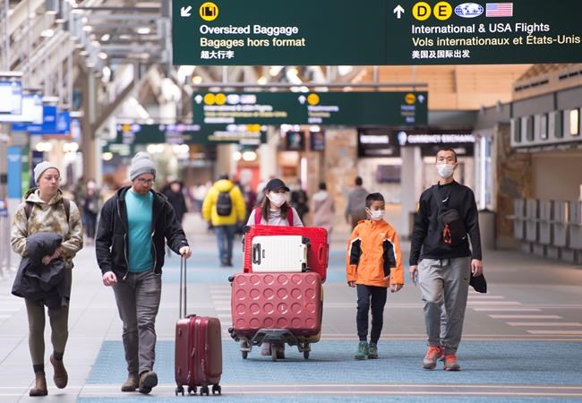 Travellers are seen at Vancouver International Airport in Richmond, B.C. Friday, March 13, 2020. The Canada Border Services Agency says it is adding new screening questions for travellers arriving in Canada, asking whether they have symptoms of COVID-19. THE CANADIAN PRESS/Jonathan Hayward