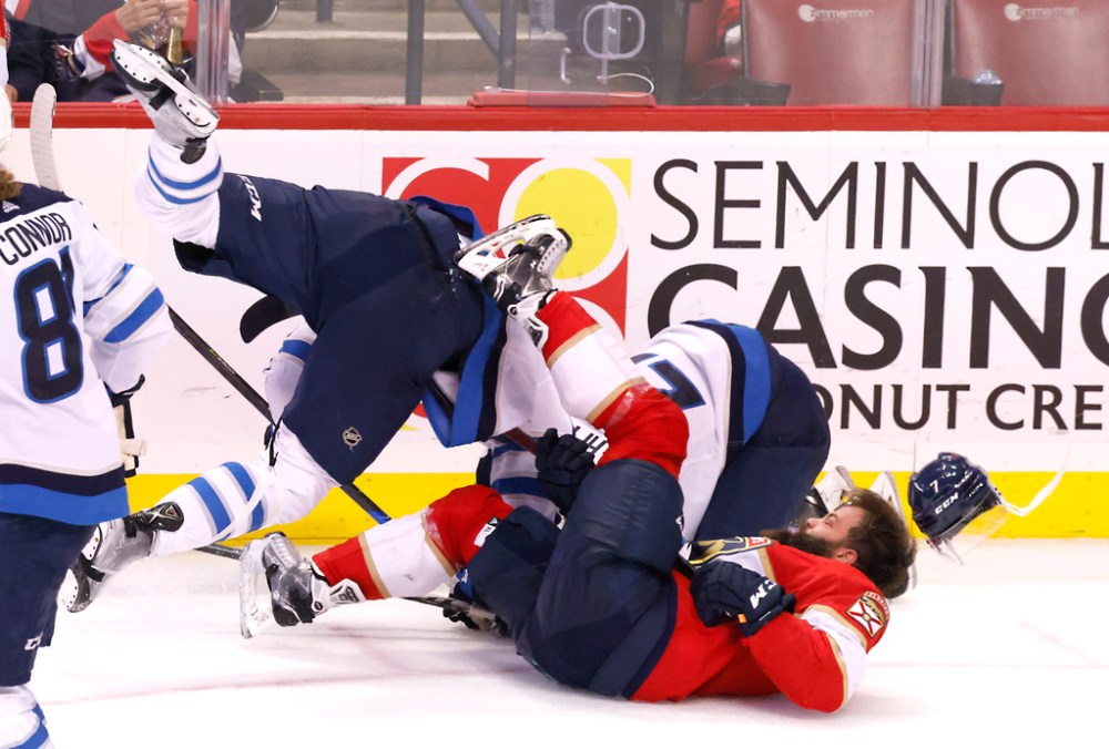 Winnipeg Jets center Mason Appleton (22) collides with Florida Panthers defenseman Radko Gudas, bottom, who looses his helmet as Winnipeg Jets center Adam Lowry, left, dives into the pile during the third period of an NHL hockey game Friday, April 15, 2022, in Sunrise, Fla. (AP Photo/Reinhold Matay)