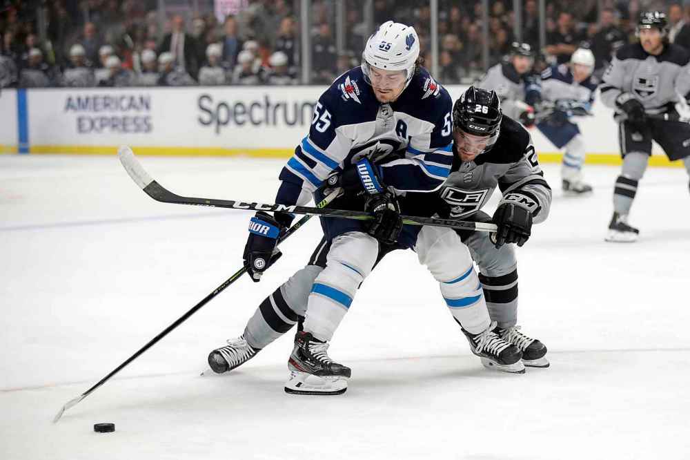 Mark Scheifele works the puck against Sean Walker Saturday in Los Angeles. (Marcio Jose Sanchez / The Associated Press)