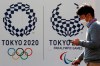 A man walks by logos of the Tokyo Olympic and Paralympic Games in Tokyo, Monday, Feb. 1, 2021. Pressure is building on Japanese organizers and the IOC to explain exactly how they plan to hold the Tokyo Olympics in the midst of a pandemic. (AP Photo/Koji Sasahara)