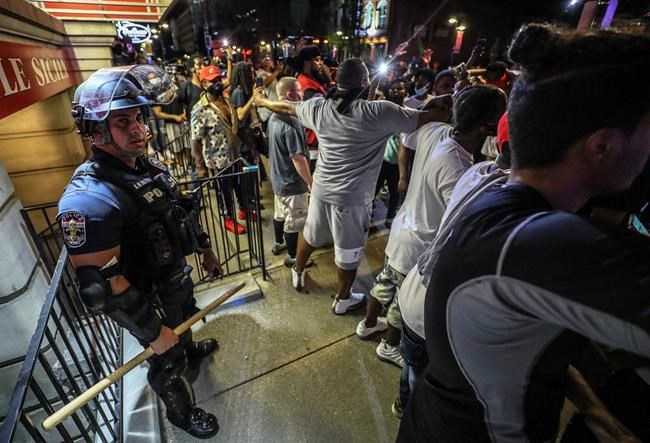 Protesters surround an LMPD officer in front of Bearno's during a protest for Breonna Taylor, Thursday, May 28, 2020 in Louisville, Ky. Taylor,  a black woman, was fatally shot by police in her home in March. The protest organizers surrounded the officer and joined arms to make sure that the crowed did not touch him. (Michael Clevenger/Courier Journal via AP)