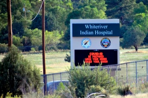 This Thursday, June 25, 2020 photo provided by C.M. Clay, shows sign at the entrance to the Whiteriver Indian Hospital in Whiteriver, Ariz., on the Fort Apache Reservation, The reservation, home to the White Mountain Apache Tribe, will be under lockdown this weekend to help slow the spread of the coronavirus. (C.M. Clay/White Mountain Apache Tribe via AP)
