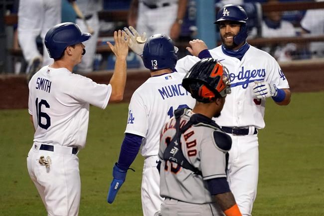 Los Angeles Dodgers' Chris Taylor, right, gets congratulations from Will Smith, left, and Max Muncy after hitting a three-run home run, with Houston Astros catcher Martin Maldonado, foreground, watching, during the eighth inning of a baseball game in Los Angeles, Sunday, Sept. 13, 2020. (AP Photo/Alex Gallardo)