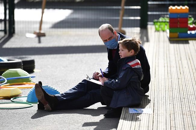 Britain's Prince William talks with a child in the playground during a visit with Kate, Duchess of Cambridge to School21, a school in east London, Thursday March 11, 2021. (Justin Tallis/Pool via AP)