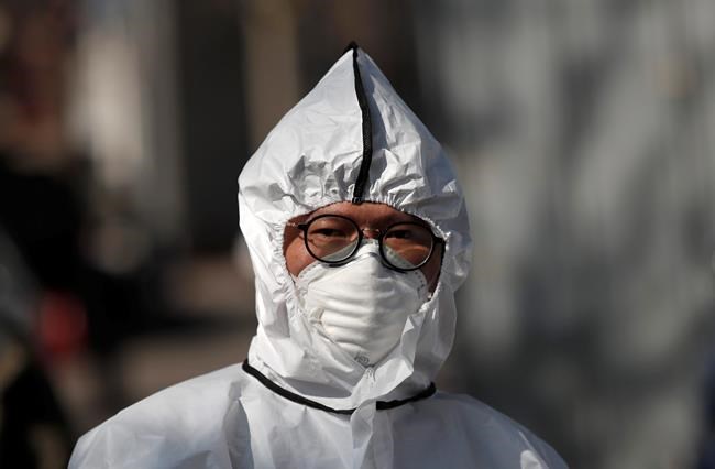 A worker wearing a protective gear prepares to spray disinfectant as a precaution against the new coronavirus in Seoul, South Korea, Monday, March 16, 2020. For most people, the new coronavirus causes only mild or moderate symptoms, such as fever and cough. For some, especially older adults and people with existing health problems, it can cause more severe illness, including pneumonia. (AP Photo/Lee Jin-man)