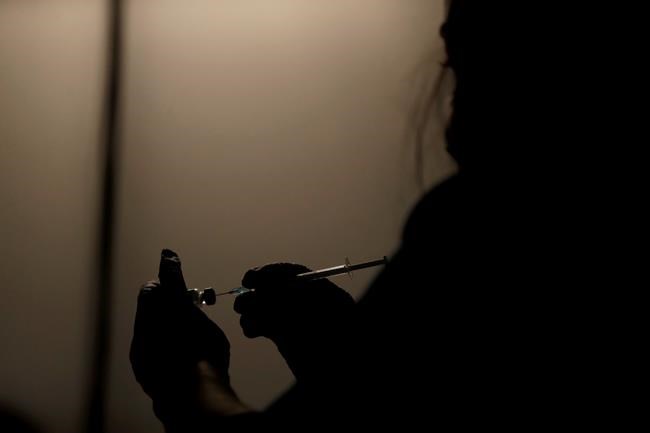 A volunteer vaccinator prepares to administer a dose of the Pfizer coronavirus vaccine at a vaccine centre in the Swaminarayan School in Neasden, north London, Saturday, May 1, 2021. (AP Photo/Matt Dunham)