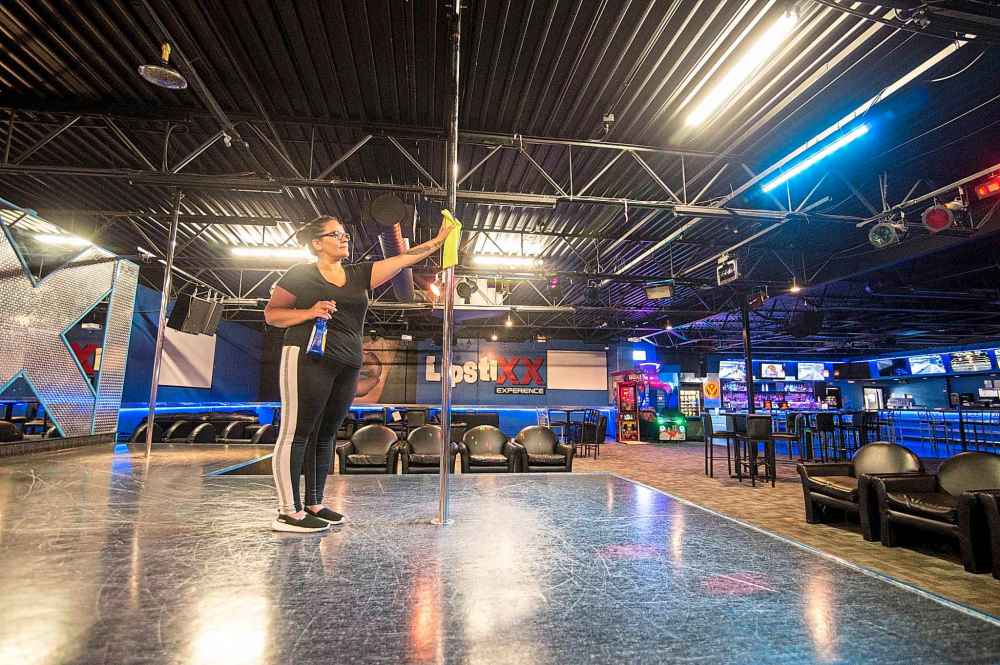 Lipstixx Experience employee Tracy Pottinger sanitizes a pole as cleaning takes place more frequently since the club has reopened amid the COVID-19 pandemic. (Mike Sudoma / Winnipeg Free Press)