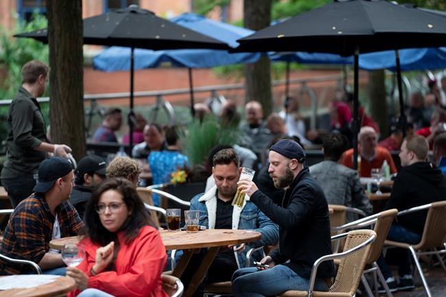 Members of the public are seen at a bar on Canal Street in Manchester's gay village, England, Saturday July 4, 2020. England is embarking on perhaps its biggest lockdown easing yet as pubs and restaurants have the right to reopen for the first time in more than three months. In addition to the reopening of much of the hospitality sector, couples can tie the knot once again, while many of those who have had enough of their lockdown hair can finally get a trim. (AP Photo/Jon Super)
