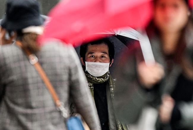 A man wears a face mask on a pedestrian street in Duesseldorf, Germany, Wednesday, Feb. 26, 2020. Authorities in western Germany said Wednesday that a man who contracted COVID-19 is in critical condition. The man with the novel coronavirus was transported to Duesseldorf's University Hospital overnight Wednesday. (AP Photo/Martin Meissner)