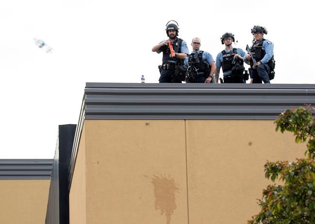 A water bottle thrown by a protester sail through the air near officers on the roof of Minneapolis Police 3rd Precinct, Wednesday, May 27, 2020, in Minneapolis. The mayor of Minneapolis called Wednesday for criminal charges to be filed against the white police officer seen on video kneeling against the neck of George Floyd, a handcuffed black man who complained that he could not breathe and died in police custody. (Carlos Gonzalez/Star Tribune via AP)