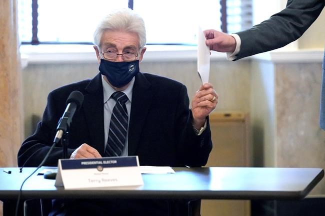 Republican Terry Reeves, a member of Mississippi's Electoral College, hands off his vote for president to a member of the Secretary of State's office, at the state Capitol in Jackson, Monday, Dec. 14, 2020. (AP Photo/Rogelio V. Solis)