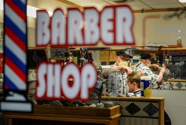 Jerel Gustafson gives Caleb Brown his first haircut in over a month at Falls Barber Shop in downtown Great Falls, Mont., on Monday, April 27, 2020. Non-essential businesses like barber shops and boutiques are reopening this week after Governor Steve Bullock announced a tiered lifting of the stay-at-home order in response to the coronavirus. (Rion Sanders/The Great Falls Tribune via AP)