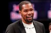 FILE - In this Dec. 26, 2019, file photo, injured Brooklyn Nets player Kevin Durant smiles as he greets teammates returning to the bench during a timeout in the second half of an NBA basketball game against the New York Knicks, in New York. Brooklyn Nets forward Kevin Durant has joined the ownership group of Major League Soccer's Philadelphia Union. Durant, a 10-time NBA All-Star, has a 5% ownership stake, with an option for 5% more in the near future, the Union announced Monday, June 15, 2020. (AP Photo/Kathy Willens, File)