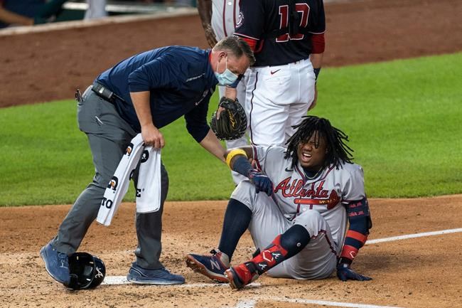 Atlanta Braves' Ronald Acuna Jr., grimaces as he is helped after fouling the ball off his left foot during the fourth inning of the team's baseball game against the Washington Nationals in Washington, Friday, Sept. 11, 2020. Acuna was helped off the field. (AP Photo/Manuel Balce Ceneta)