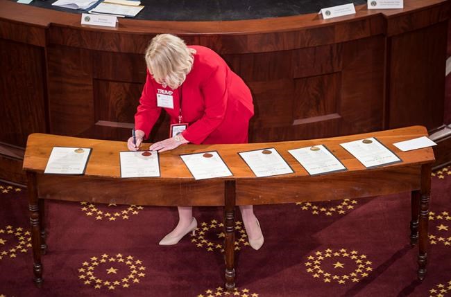 Elector Michele Nix signs Electoral College ballots for President Donald Trump and Vice President Mike Pence in the house chambers of the Old State Capitol building in Raleigh, N.C., on Monday, Dec. 14, 2020. (Julia Wall/The News & Observer via AP)
