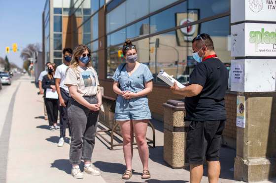 MIKAELA MACKENZIE / WINNIPEG FREE PRESSSisters Sophie (left) and Anica Warkentine line up to get vaccinated at the Ma Mawi Wi Chi Itata Centre walk-in clinic in Winnipeg on Wednesday, the day eligibility expanded to include all Manitobans over age of 18.