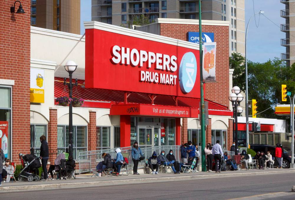 MIKE DEAL / WINNIPEG FREE PRESS Hundreds line-up early Monday morning in the hopes of getting a Pfizer vaccine after the Shoppers Drug Mart in Osborne Village posted signs last week saying they would be accepting walk-ins from the 21st to the 25th between 9-4pm. By 8am the line-up was all the way around the block. 210621 - Monday, June 21, 2021.