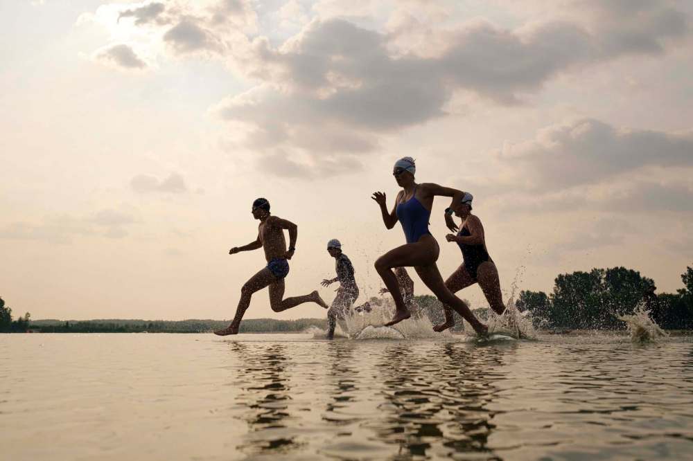 Triathlon Manitoba athletes run out to swim a lap during a practice in Birds Hill Park on Tuesday. (Mike Sudoma / Winnipeg Free Press)