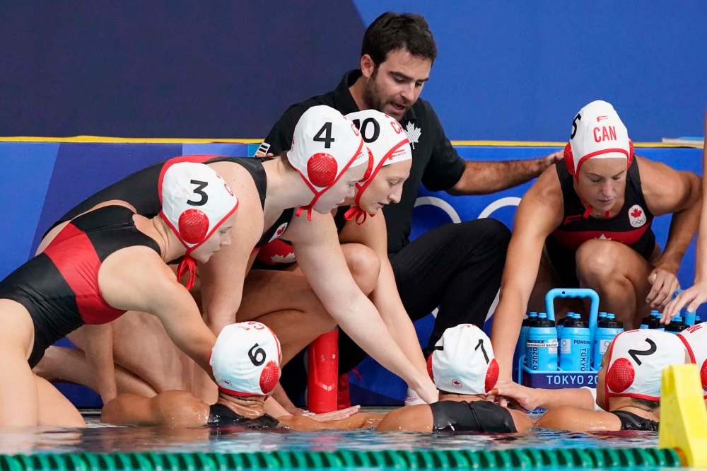 Canada head coach David Paradelo gathers his players together during a timeout in a preliminary round women's water polo match against South Africa at the 2020 Summer Olympics, Wednesday, July 28, 2021, in Tokyo, Japan. (AP Photo/Mark Humphrey)