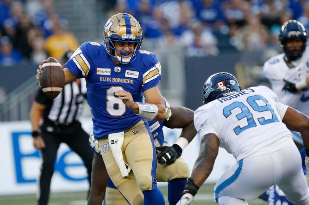 Winnipeg Blue Bombers quarterback Zach Collaros scrambles away from Toronto Argonauts' Charleston Hughes during the first half. THE CANADIAN PRESS/John Woods