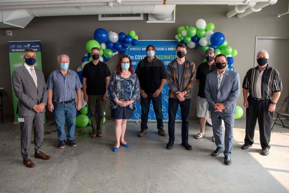 Manny Atwal, president and CEO of Manitoba Liquor and Lotteries, and Crown Services Minister Jeff Wharton, with winners of the Vax to Win Lottery. (Alex Lupul / Winnipeg Free Press)