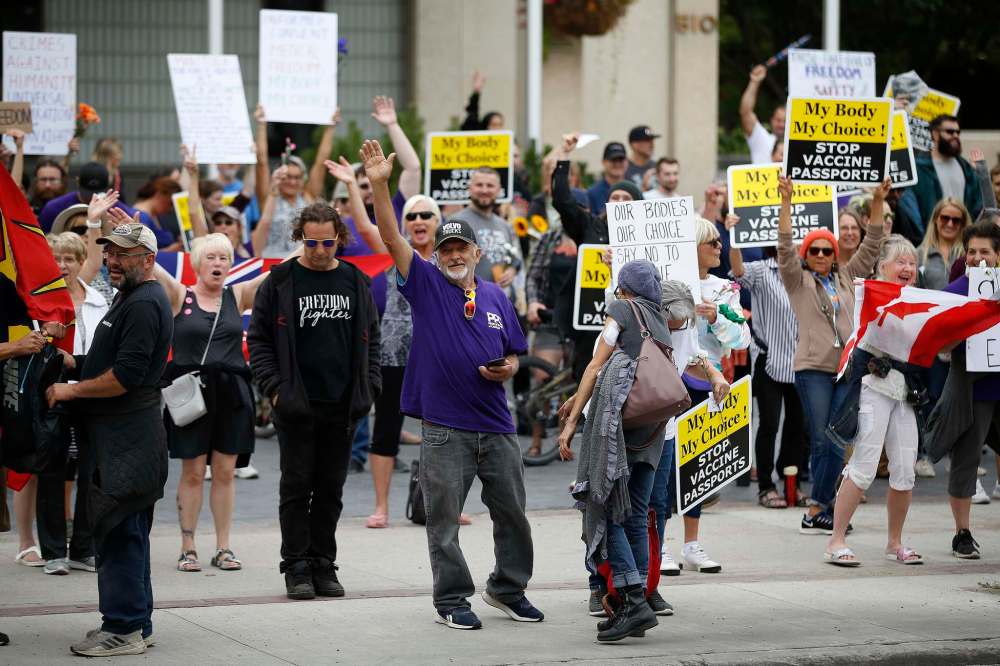 Protestors waves to passing vehicles outside of city hall, where they stood in silence for 30 minutes. (John Woods / Winnipeg Free Press)