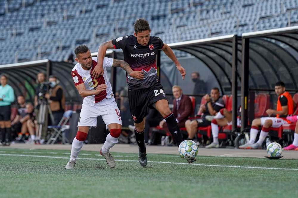 Valour FC midfielder Kevin Aleman (left) tackles Cavalry FC’s David Norman Saturday afternoon at IG Field. Below, Valour’s Sean Rea tries to put the ball past Cavalry’s Jose Escalante. (Robert Reyes Ong / Valour FC)