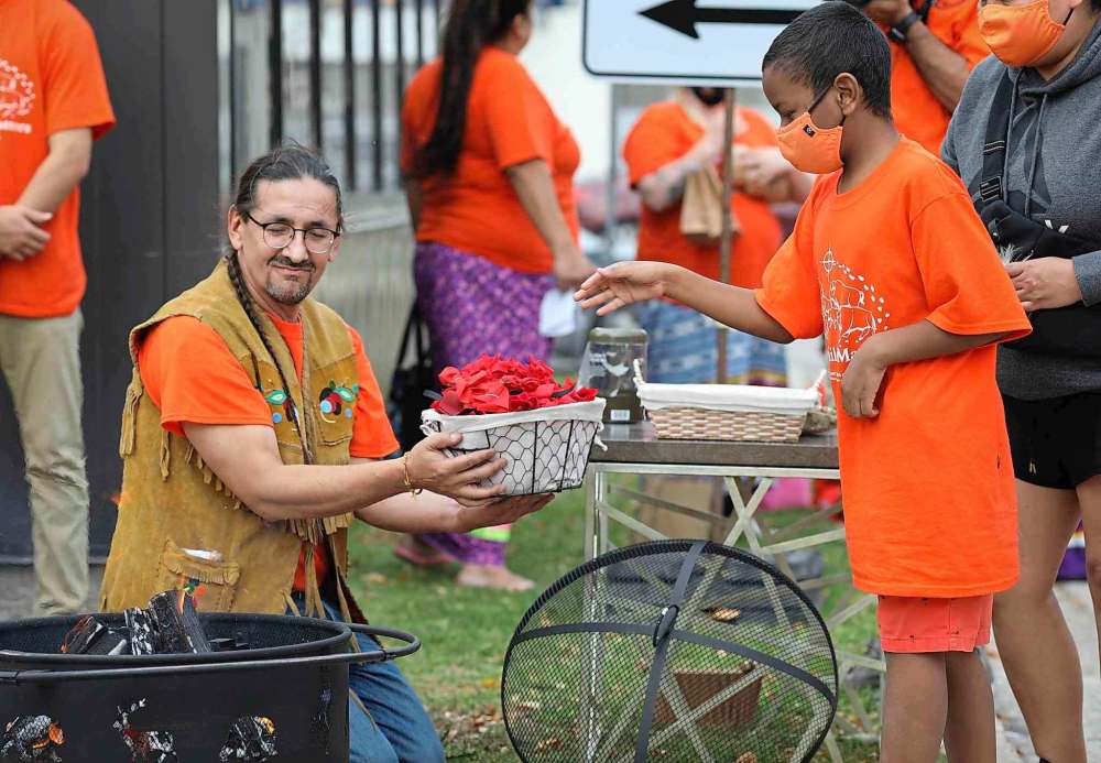 Fire keeper Richard Shrupka offers tobacco bundles for the public to throw into a sacred fire at Ma Mawi Wi Chi Itata Centre on Thursday. (Jessica Lee / Winnipeg Free Press)