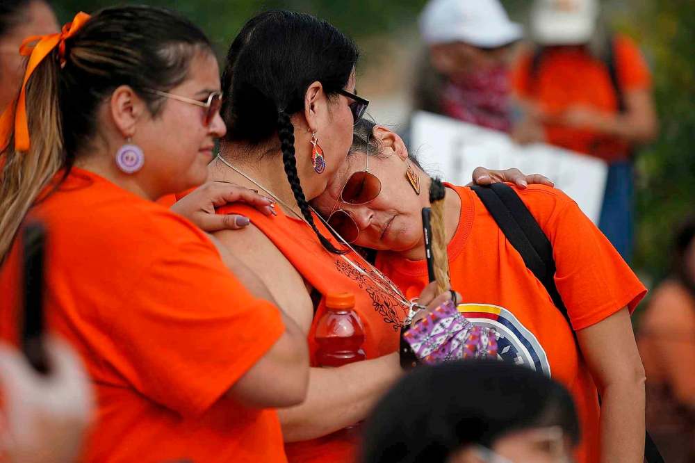 People comfort each other as Residential School and Sixties Scoop survivors are honoured on the steps of the Canadian Museum for Human Rights on Thursday. (John Woods / The Canadian Press)