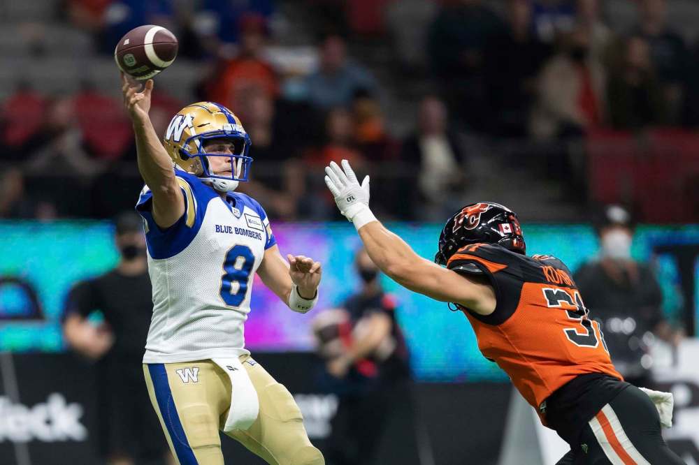 Winnipeg Blue Bombers quarterback Zach Collaros, left, passes over B.C. Lions' Adam Konar during the first half of a CFL football game in Vancouver, on Friday, October 1, 2021. THE CANADIAN PRESS/Darryl Dyck