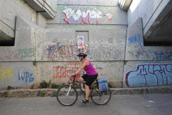 JESSICA LEE / WINNIPEG FREE PRESSA woman bikes past a sign under the Norwood Bridge which says no camping and no fires.