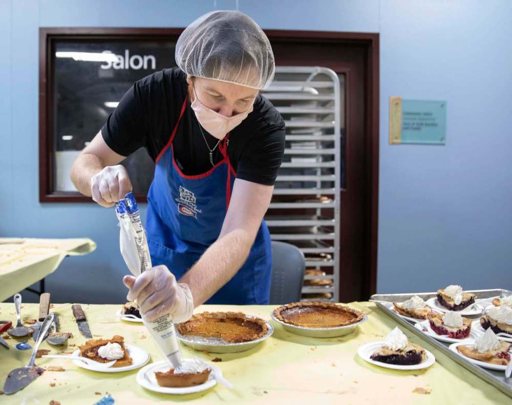 Dallas Holden adds whipped cream to plates of pie at Siloam Mission on Friday during its annual Thanksgiving lunch. (Jessica Lee / Winnipeg Free Press)