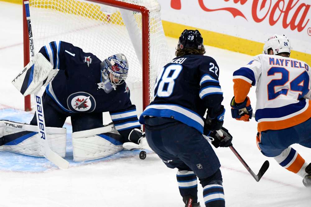 Winnipeg Jets goaltender Eric Comrie (1) makes a save on New York Islanders’ Scott Mayfield (24) during the first period. (Fred Greenslade / The Canadian Press)