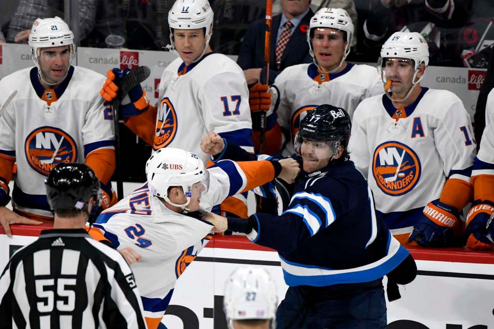 Winnipeg Jets' Adam Lowry (17) fights with New York Islanders’ Scott Mayfield (24) in front of the Islanders bench during the second period.(Fred Greenslade / The Canadian Press)