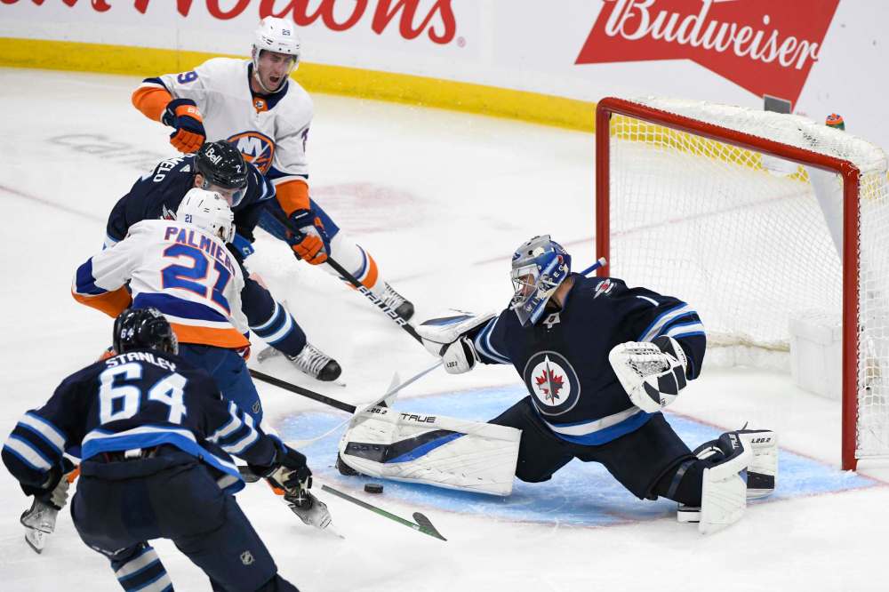 Winnipeg Jets goaltender Eric Comrie (1) makes a save on New York Islanders’ Kyle Palmieri (21) during the third period of NHL action in Winnipeg on Saturday, November 6, 2021. (Fred Greenslade / The Canadian Press)