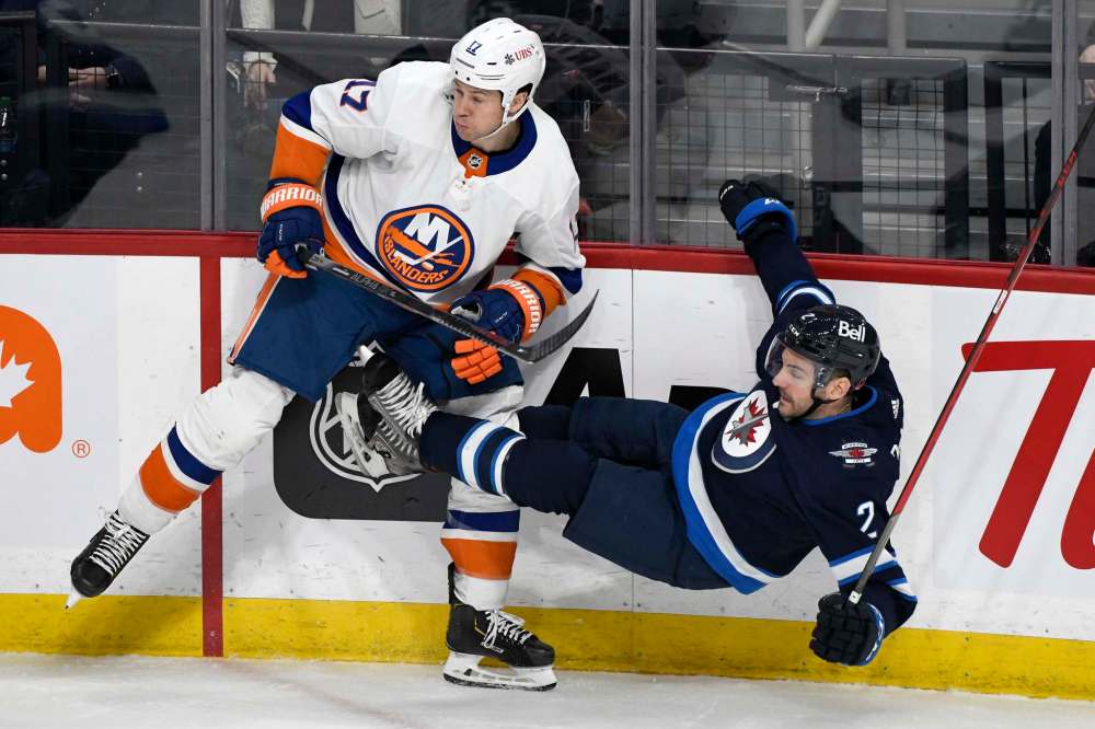 Winnipeg Jets' Dylan DeMelo (2) is checked by New York Islanders' Matt Martin (17) during the first period. (Fred Greenslade / The Canadian Press)