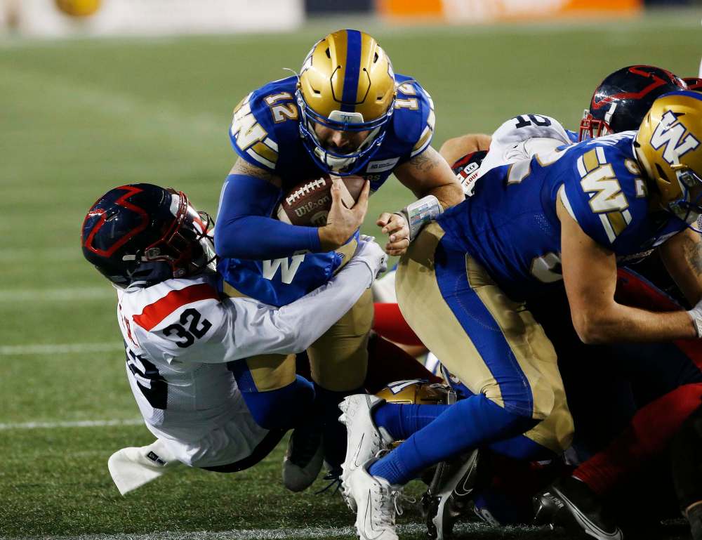 Winnipeg Blue Bombers quarterback Sean McGuire (12) goes for the short yardage touchdown against the Montreal Alouettes’ Rodney Randle Jr. (32) during the second half. (John Woods / The Canadian Press)