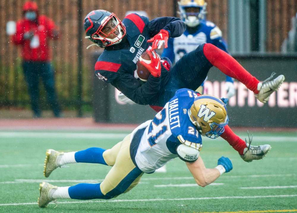Montreal Alouettes' Reggie White Jr., (84) is upended by Winnipeg Blue Bombers' Nick Hallett during the second half. (Graham Hughes / The Canadian Press)