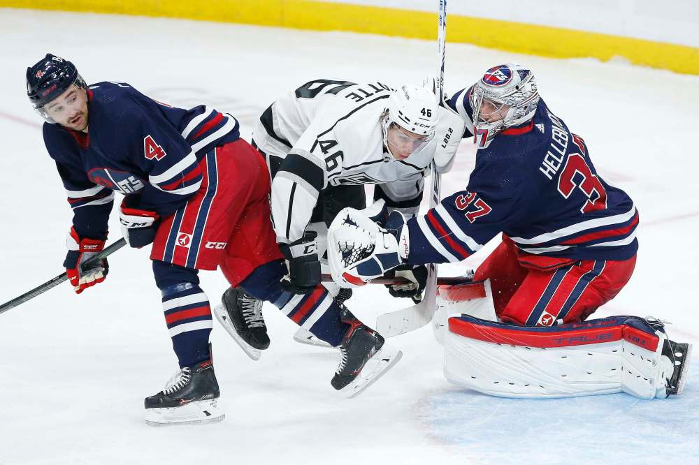 Winnipeg Jets goaltender Connor Hellebuyck (37) saves the shot as Neal Pionk (4) and Los Angeles Kings' Blake Lizotte (46) collide during third period NHL action in Winnipeg on Saturday, November 13, 2021. (John Woods / The Canadian Press files)
