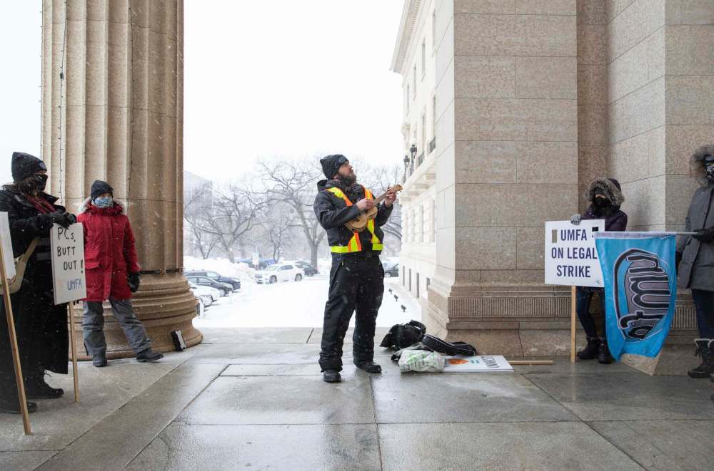 Strike captain Michael Minor leads a group of UMFA members in a song about solidarity in front of the legislative building on Wednesday. (Jessica Lee / Winnipeg Free Press)